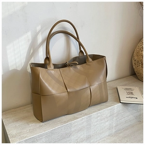 Detail of wide-woven leather texture on a khaki tote bag with minimalist slim tie closure