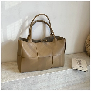 Detailed close-up of large weave khaki tote bag with double handles and tied closure