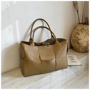 Close-up of the woven leather texture and khaki checkered detail on the tote bag