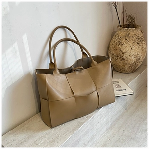 Close-up of khaki woven leather tote bag showing intricate geometric patterns and texture