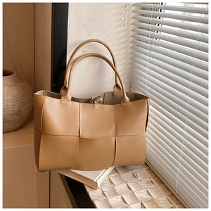 Detail view of the camel woven leather tote with wide strips and long shoulder handles