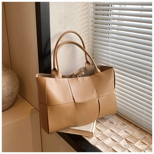 Detail of light brown woven tote bag with large weave pattern and cylindrical handles