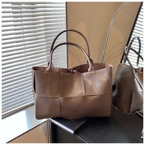 Close-up of brown grid-weave tote bag with matte leather texture and sturdy handles