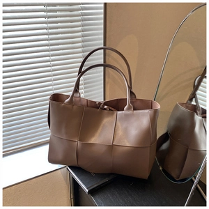 Detail of tan woven leather tote bag featuring large scale weave and tie-closure