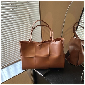 Detail of wide caramel woven PU leather tote with soft matte finish and knot detail