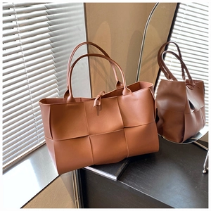 Detail of caramel brown wide-weave leather tote bag with hand-woven texture and handles