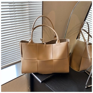 Macro shot of large woven tote bag in apricot PU leather with dual handles and tie closure