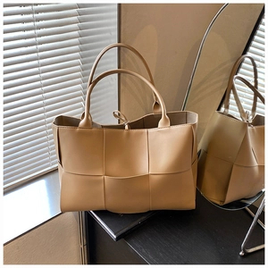 Detailed weave pattern of the beige tote bag on a wooden surface with a mirror reflection