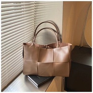 Macro view of khaki woven tote bag showing luxury texture and double handle detail