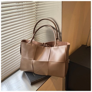 Detailed view of the woven taupe leather tote bag texture under natural light shadows