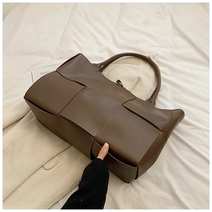 Detail of dark brown large woven tote bag featuring soft leather wide grid craft