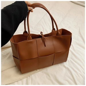 Detail of caramel brown hand-woven leather tote bag with classic large lattice weave