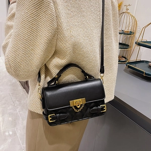 Elegant black quilted crossbody bag with gold chain strap and top handle on model