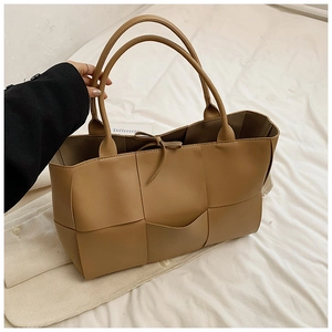 Close-up of khaki woven tote bag showing wide Intrecciato texture and slim shoulder straps