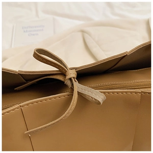 Detail of khaki woven leather tote showing fine stitching and leather drawstring closure