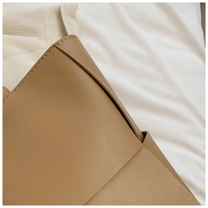 Macro shot of precise stitching and premium leather texture on the woven tote bag
