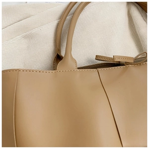 Close-up of dual handles and fine stitching on the beige woven leather tote bag
