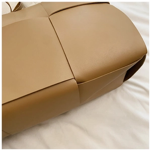 Detailed close-up of large caramel woven texture and leather craftsmanship on tote bag