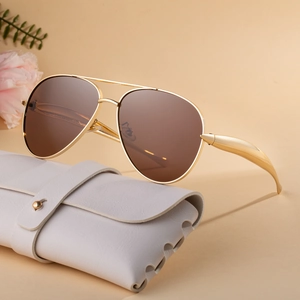 Retro aviator metal sunglasses with brown lenses and a white leather case on a beige background
