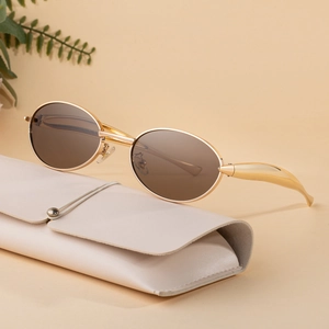 Oval gold metal sunglasses with brown lenses and a cream textured leather case