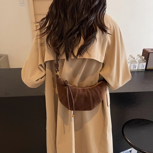 Deep brown suede croissant bag shown as a crossbody on a trench coat model