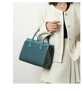 Detailed view of teal leather tote bag with crocodile texture trim and gold hardware
