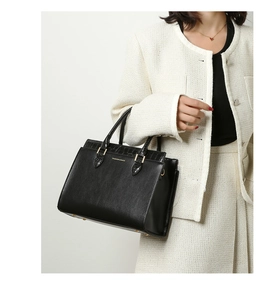 Detail of black tote bag featuring faux crocodile texture and gold hardware on handles