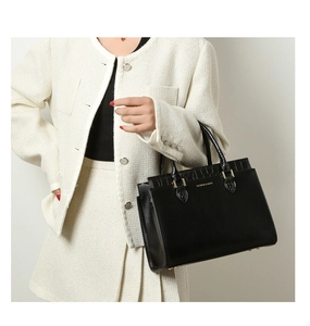 Detail of black faux leather tote featuring crocodile pattern and gold lettering