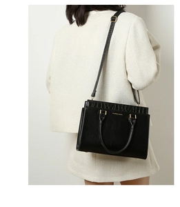 Close-up of black leather tote bag featuring crocodile pattern and gold brand lettering