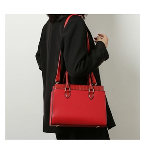 Detail of red leather handbag with crocodile pattern flap and detachable shoulder strap