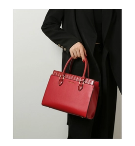 Close-up of red leather tote bag with crocodile pattern and golden metal hardware