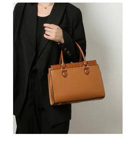Detail of a brown tote bag featuring luxury crocodile texture and gold hardware accents
