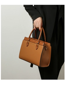 Detail of a brown tote bag featuring lychee grain leather and faux crocodile trim texture