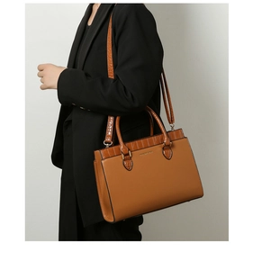 Detail of tan faux leather tote bag with crocodile pattern trim and gold-tone hardware