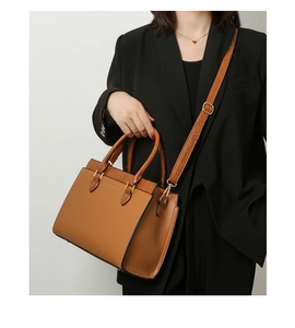 Detail of brown tote bag showing crocodile texture contrast and gold logo lettering