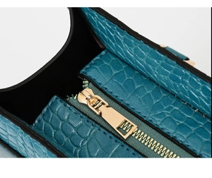 Close-up of teal crocodile embossed leather tote bag with premium gold zipper detail