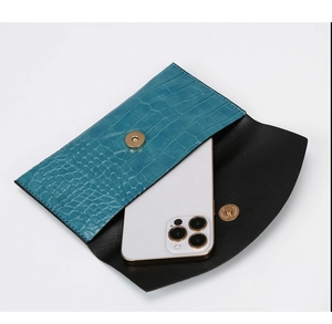 Detailed view of teal crocodile pattern envelope clutch with golden magnetic clasp closure