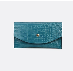 Detail of teal faux crocodile texture on a minimalist clutch with a gold snap button