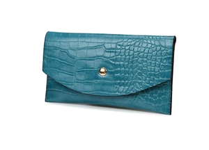 Detailed macro view of teal crocodile-textured leather wallet with gold metal fastener