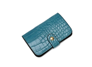 Detail of teal crocodile embossed small folding wallet with golden round metal buckle