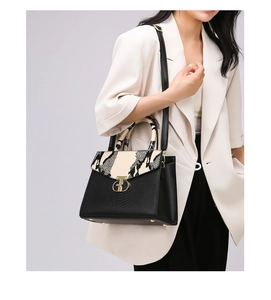 Macro detail of elegant black leather handbag featuring animal print flap and gold clasp