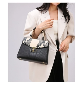 Close-up of black leather handbag with faux snakeskin flap and golden metal clasp