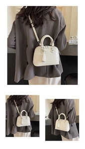 Macro detail of white faux-leather shell bag showing texture and adjustable shoulder strap