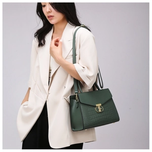 Detail of dark green crocodile pattern handbag paired with a stylish beige suit jacket