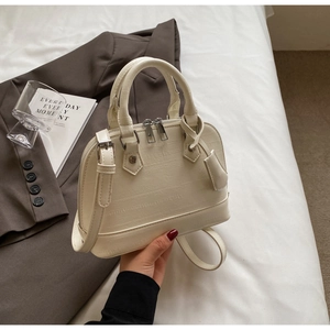 Close-up of cream shell bag with crocodile pattern and textured leather details