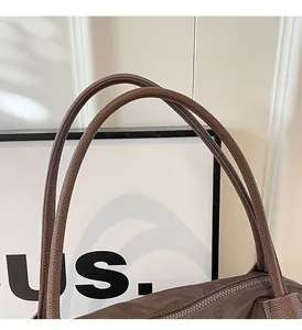 Close-up of brown tote bag showing the leather handle and metal zipper detail