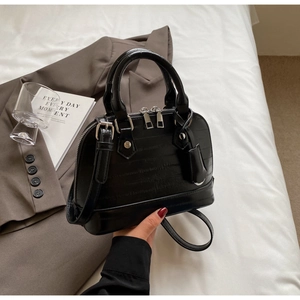 Detail of black faux-crocodile leather texture and silver zipper on women's shell bag