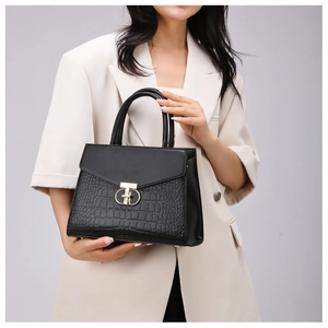 Close-up of black handbag with faux crocodile leather and elegant golden metal buckle