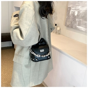 Detail of black pleated box bag with chunky silver chain strap on a chic model
