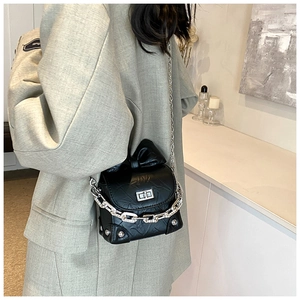 Detail of quilted black box bag featuring silver twist lock and chic bow decoration